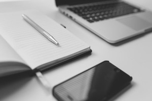 Stôl na ktorom sa nachádzajú: zápisník, mobilný telefón a notebook